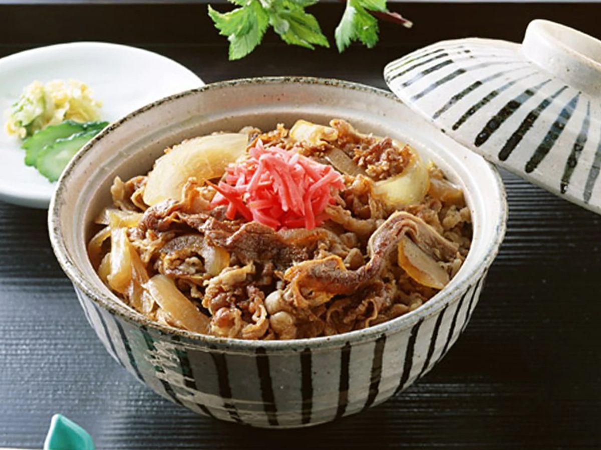 Gyudon beef rice bowl with sliced beef, onions, pickled ginger in ceramic bowl