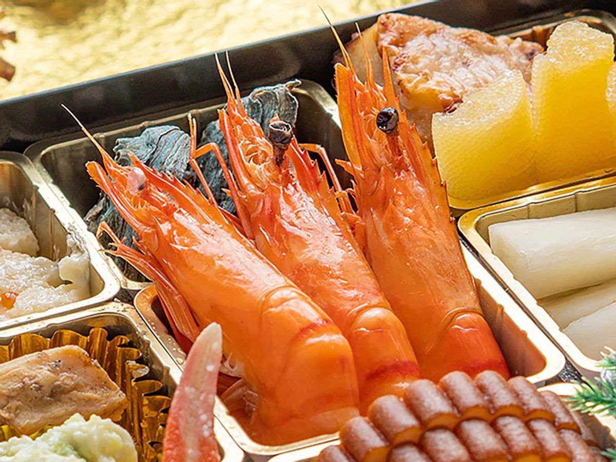 Large cooked prawns displayed in white containers with various seafood and side dishes at buffet