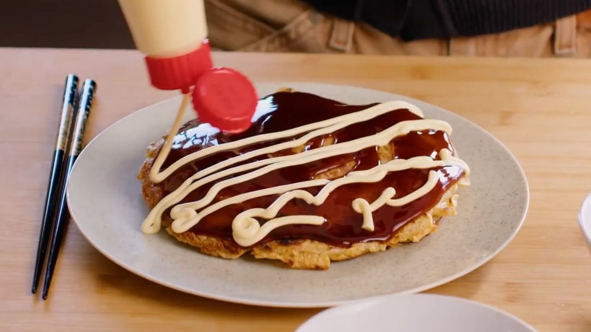Chocolate-drizzled pastry dessert on white plate with chopsticks and red condiment container