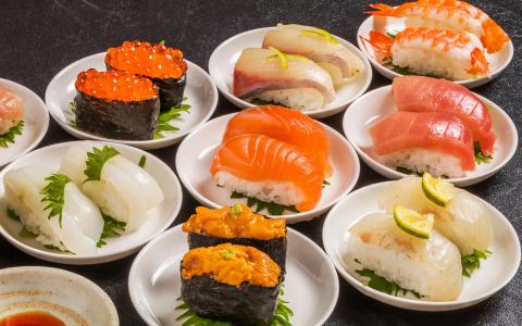 Assorted nigiri sushi selection with salmon, ikura, scallop, and uni on white plates