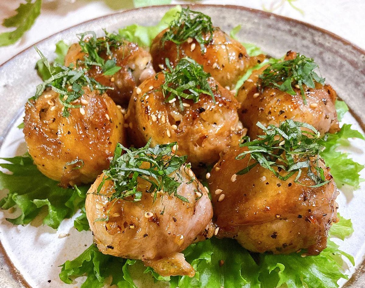 Glazed meatballs with sesame seeds and fresh herbs on lettuce bed