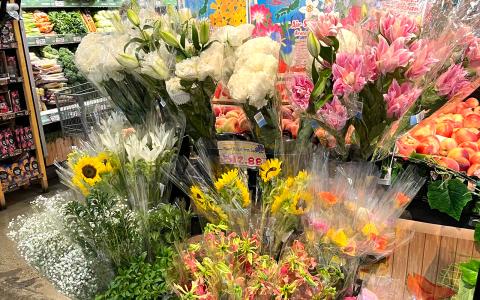 Flower shop display with white peonies, pink carnations, sunflowers, and seasonal blooms