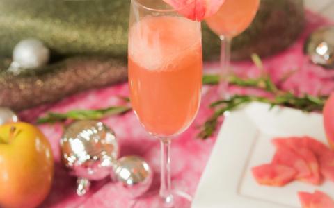 Elegant cocktails with pink flower garnish, festive holiday table setting with ornaments