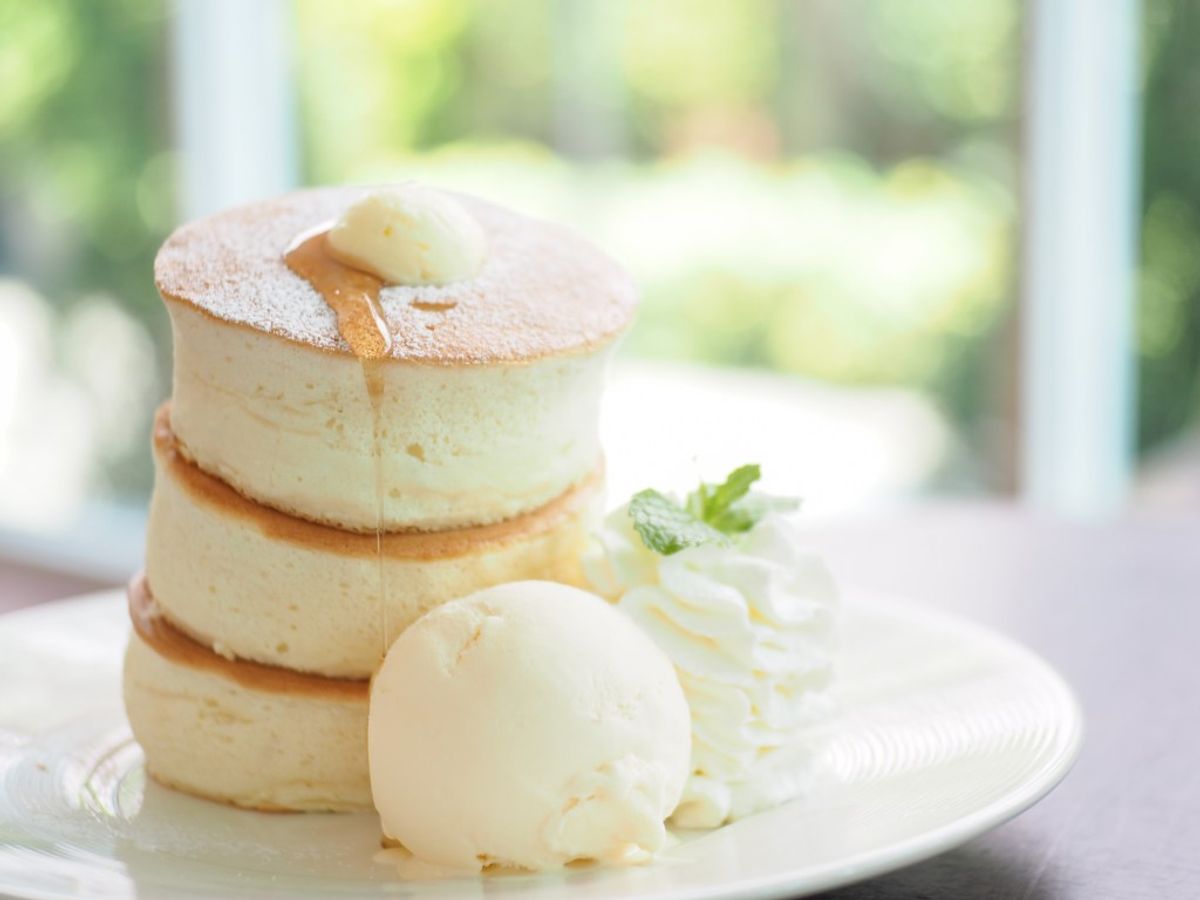Fluffy soufflé pancakes stacked with vanilla ice cream and butter on white plate