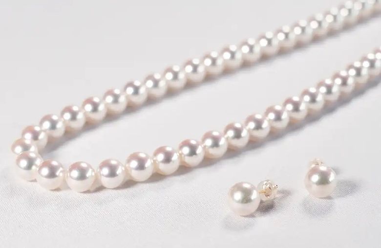 Pearl necklaces and matching earrings displayed on white background