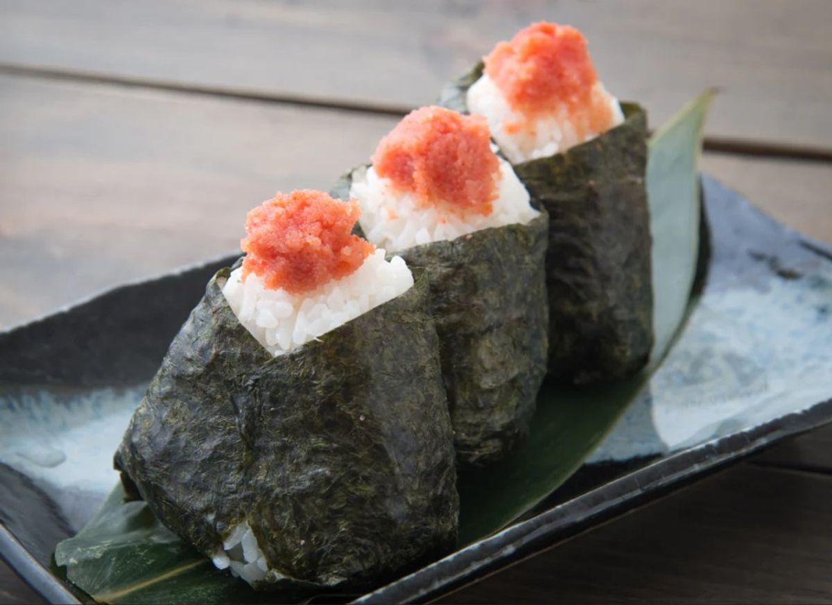 Three pieces of nigiri sushi with ikura salmon roe topped on nori seaweed, served on a black plate