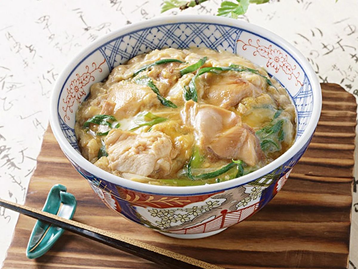 Oyakodon with chicken and egg in decorative blue and white ceramic bowl with chopsticks