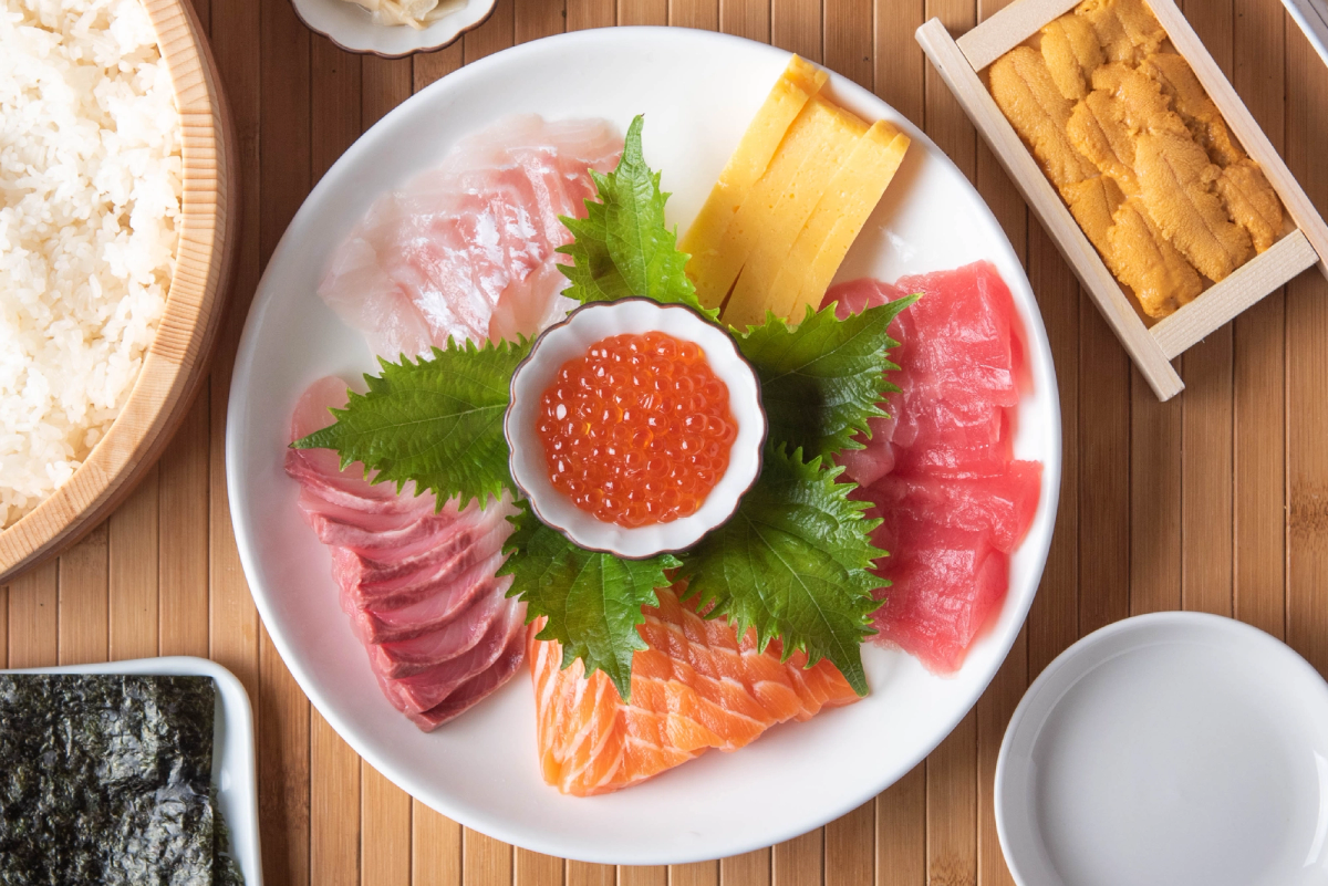 Sashimi platter with ikura, salmon, tuna, and bamboo shoot on wooden table