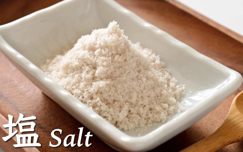 Salt in white ceramic dish with Japanese and English labels on wooden surface