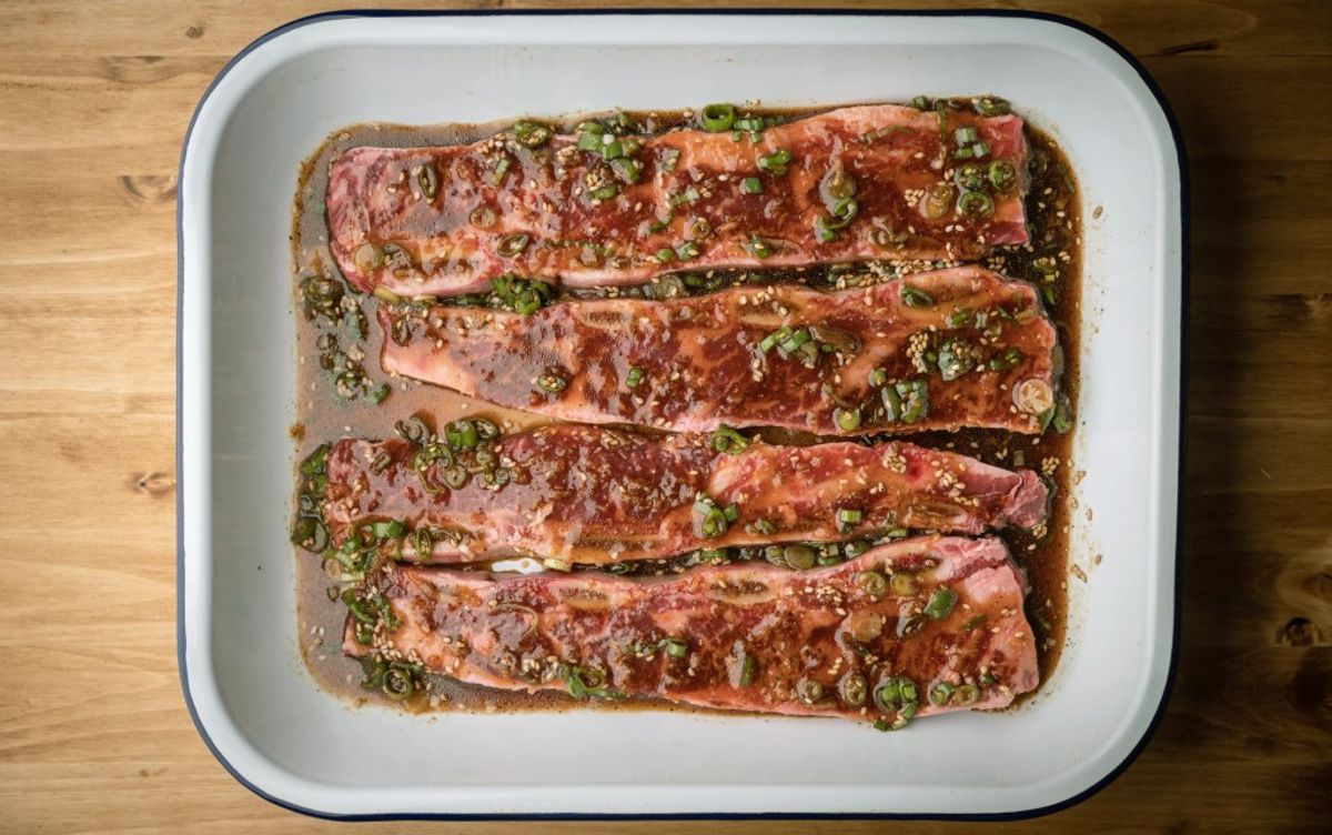 Four raw salmon fillets topped with chopped green onions in white baking dish