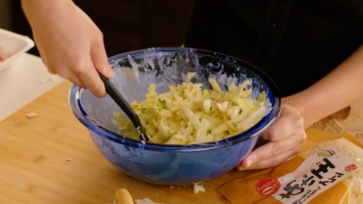 Person mixing diced onions in blue bowl with spatula during food preparation