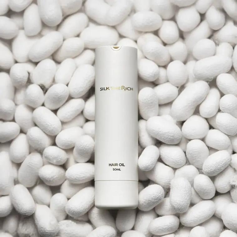 Silk Rich hair oil 50mL bottle on white pebble background