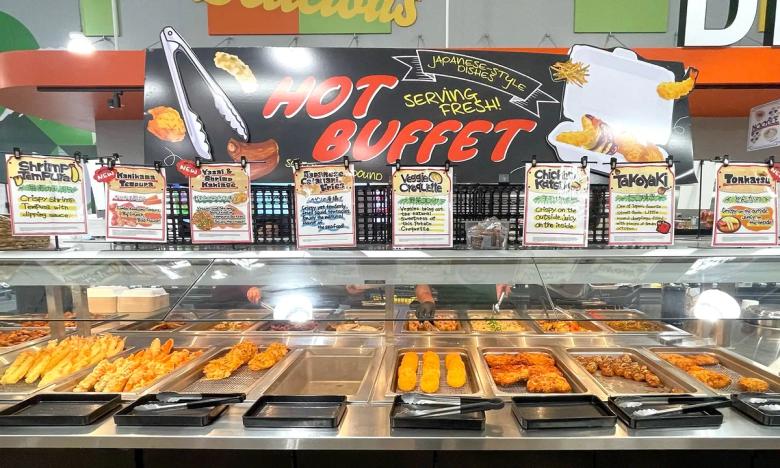 Japanese hot buffet display case with fried chicken, tempura, and various prepared dishes