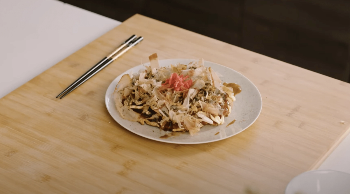 Stir-fried noodles with vegetables and pickled ginger on white plate with chopsticks