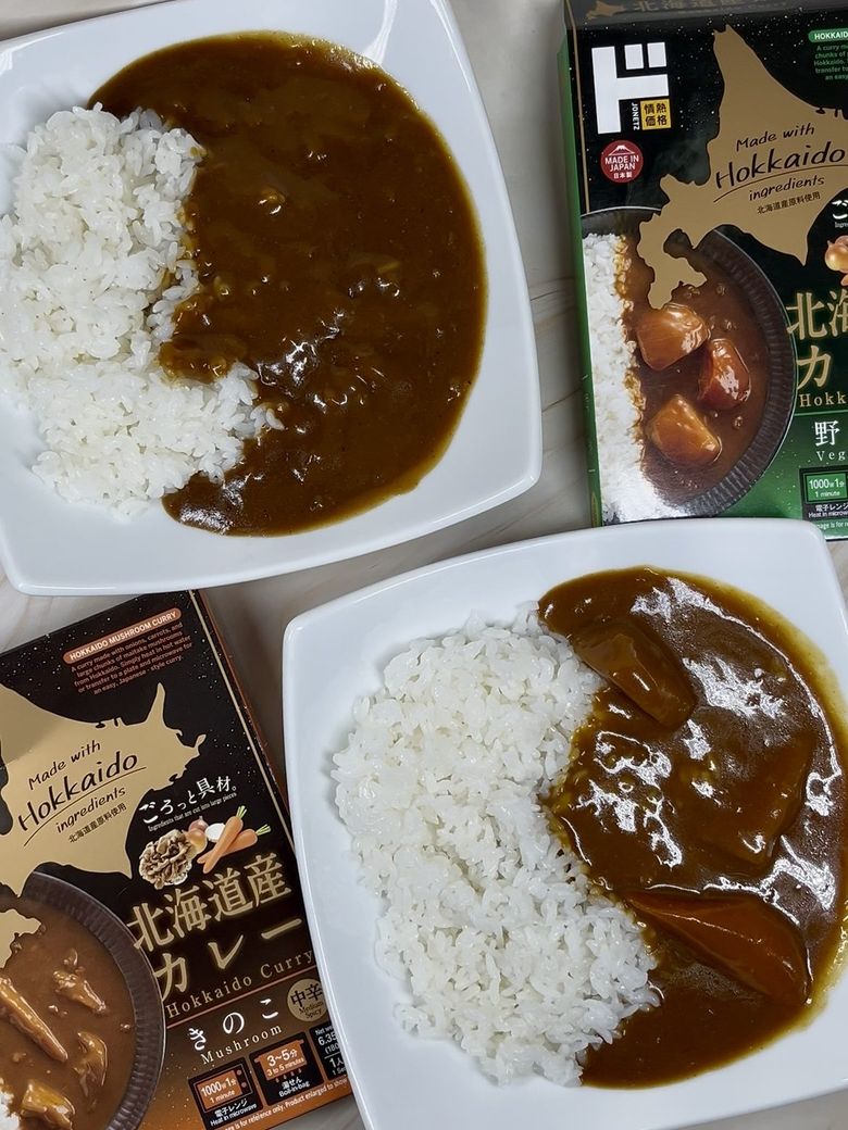 Two bowls Hokkaido curry rice with mushrooms, packaged curry boxes displayed alongside