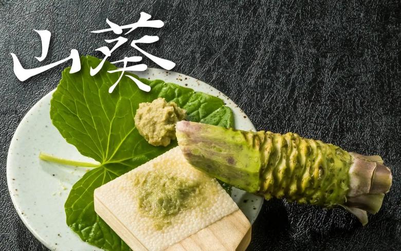 Wasabi root and grated wasabi powder on white plate with shiso leaf