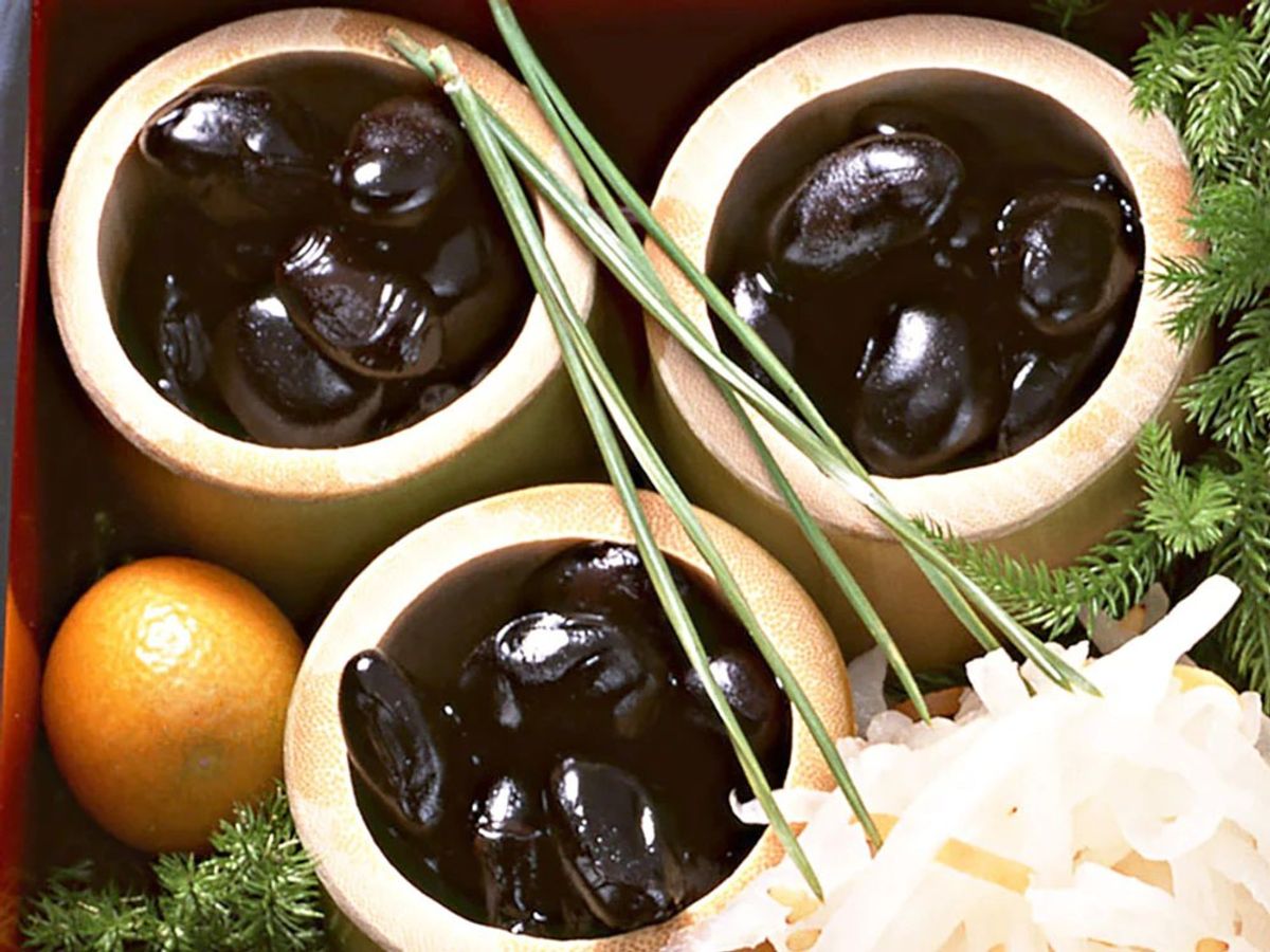 Black olives in ceramic bowls with citrus, herbs, and cheese garnish