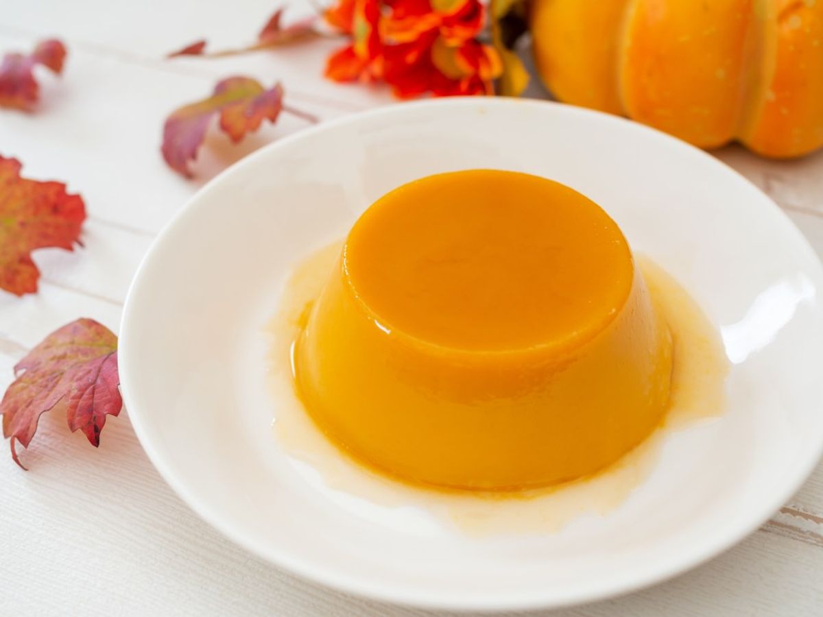 Pumpkin flan dessert on white plate with autumn decoration and pumpkins