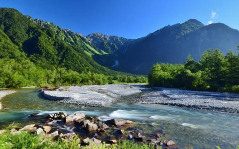 Mountain river valley with clear turquoise water and lush green forests surrounding rocky terrain