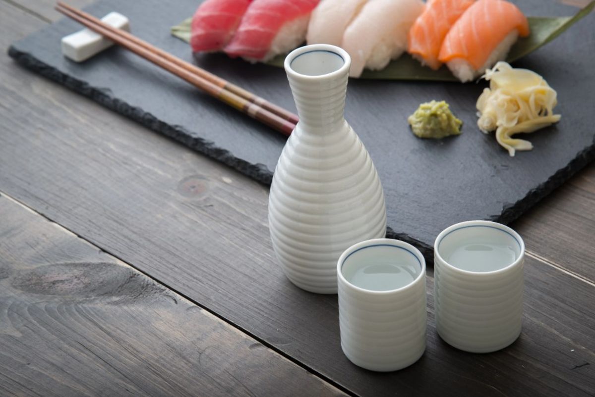 Sake set with sushi platter on dark slate, chopsticks and condiments displayed