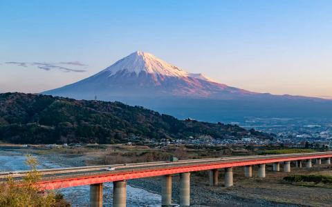 Mount Fuji with red bridge, river, and surrounding landscape at sunrise