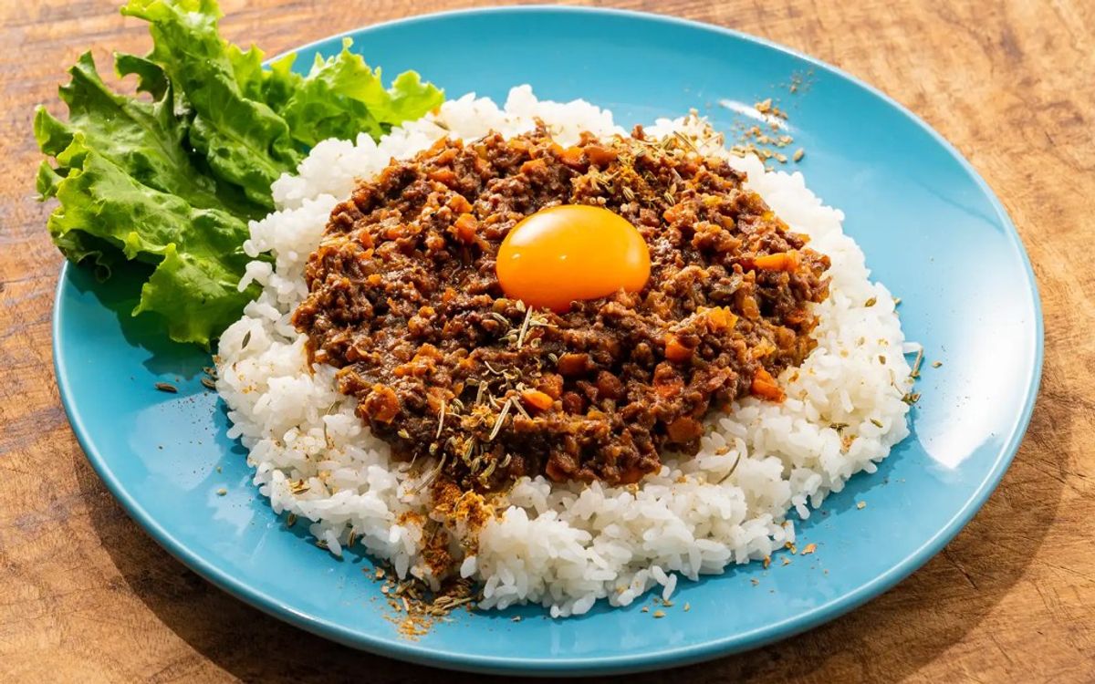 Bibimbap with ground beef, egg yolk, and fresh lettuce on blue plate