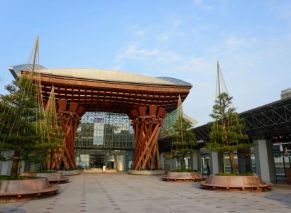 Large red wooden gate structure with curved roof and hanging plants in plaza area