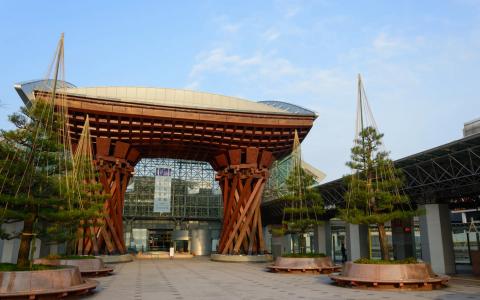 Large red wooden gate structure with curved roof and hanging plants in plaza area