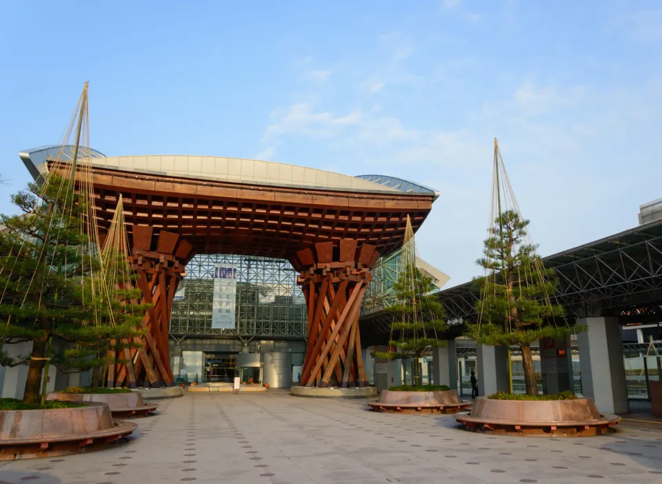 Large red wooden gate structure with curved roof and hanging plants in plaza area