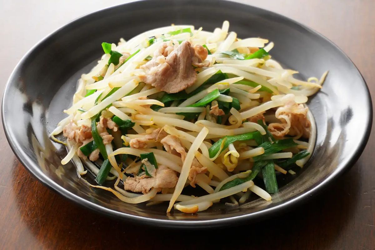 Bean sprout stir-fry with pork and green onions in gray bowl