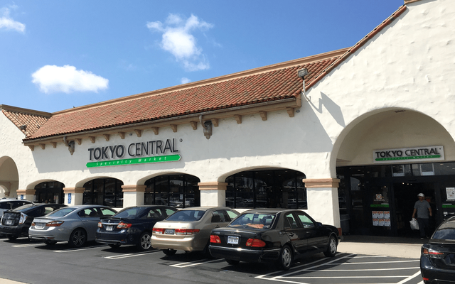 Tokyo Central storefront with parking lot, white building with tile roof and arched entrance
