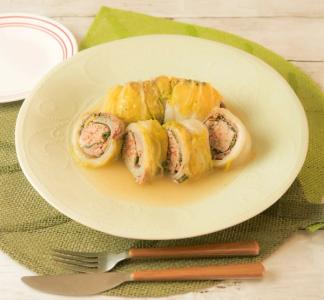 Stuffed squid rolls with meat filling served in broth on white plate