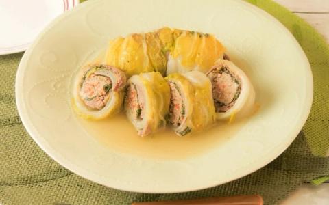 Stuffed squid rolls with meat filling served in broth on white plate