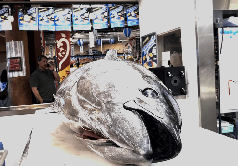 Fish head display at Japanese grocery store counter with staff visible in background