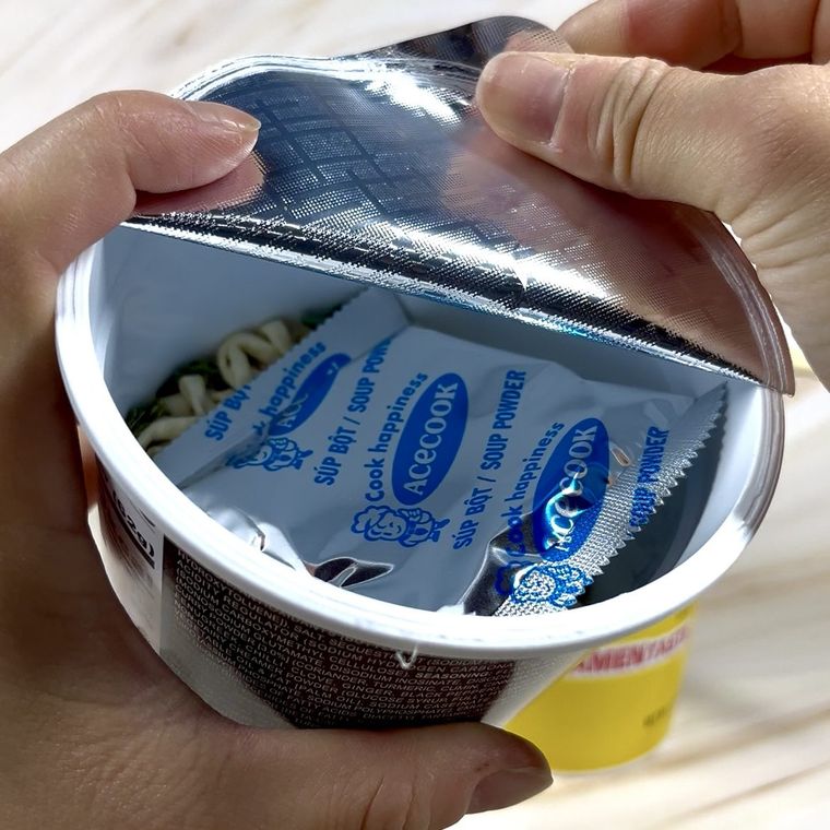 Person holding opened packaged food item with blue foil wrapping and yellow label visible