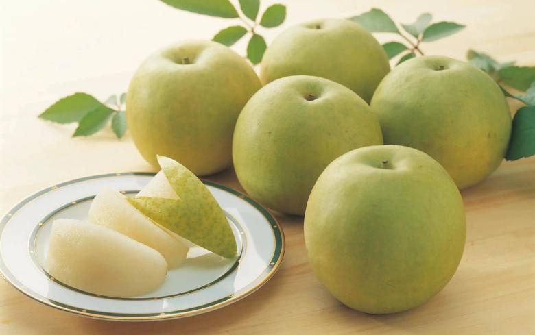 Green apples with leaves and sliced apple on white plate with decorative rim