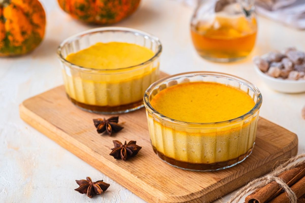 Pumpkin custard tart desserts with star anise and cinnamon garnish on wooden board