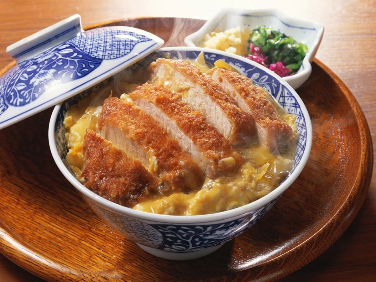 Katsudon with breaded pork cutlet over rice in blue and white porcelain bowl