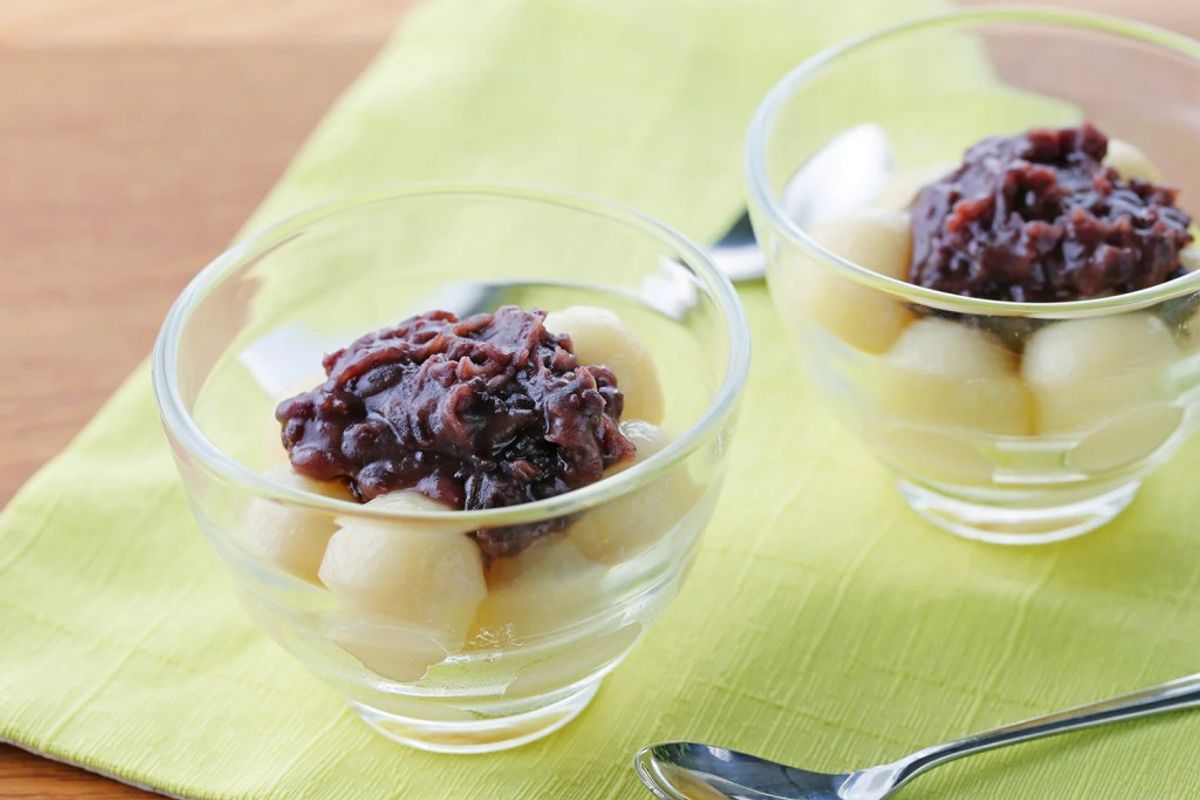 Two glass cups with red bean paste topping and white mochi on yellow placemat