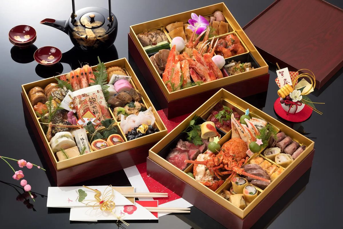 Four luxury bento boxes with seafood, sashimi, and traditional Japanese dishes arranged with tea set