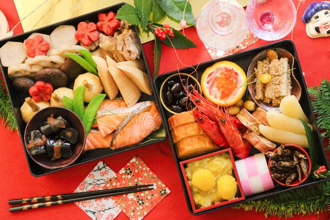 Elaborate Japanese New Year osechi bento boxes with seafood, vegetables, and traditional dishes on red background