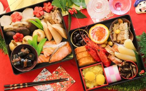 Elaborate Japanese New Year osechi bento boxes with seafood, vegetables, and traditional dishes on red background