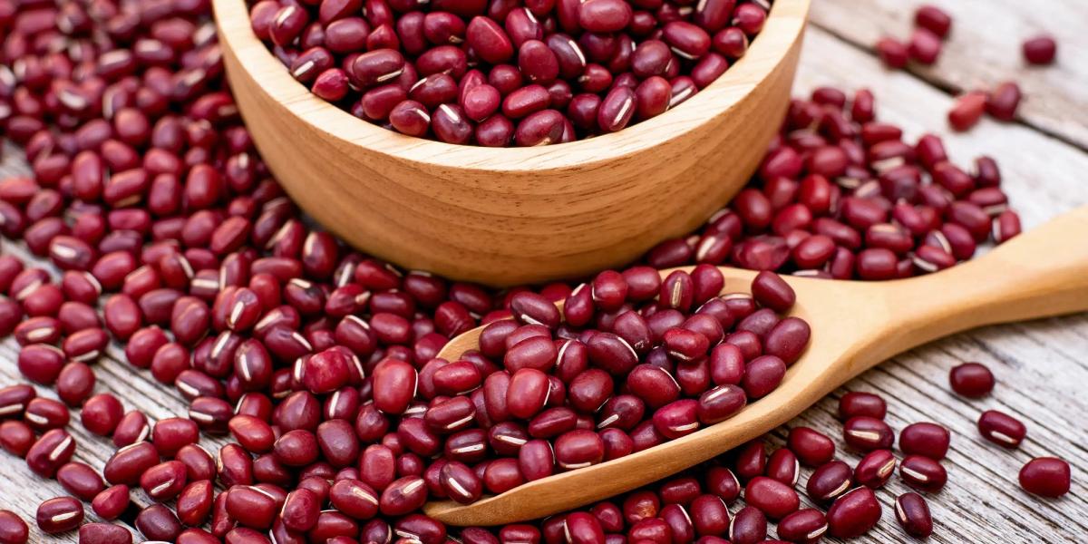 Red beans in wooden bowl and spoon on white wooden table