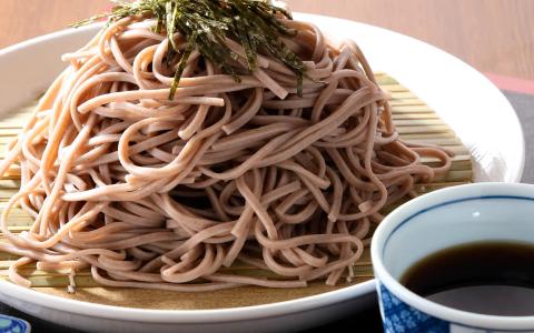 Soba noodles with nori garnish, dipping sauce, and bamboo mat presentation