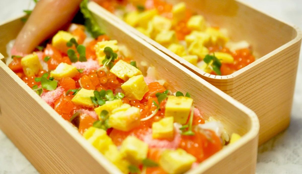 Colorful sushi or poke bowls with salmon, avocado, and green onions in wooden containers