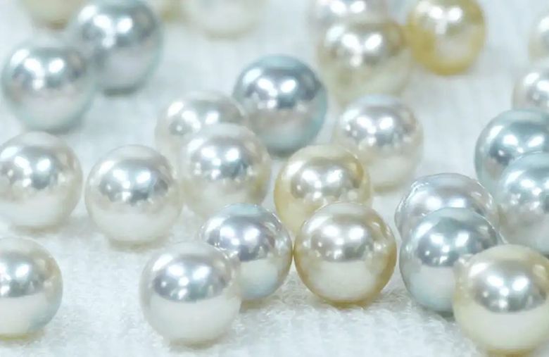 Pearl-like beads in white and silver tones scattered on white surface