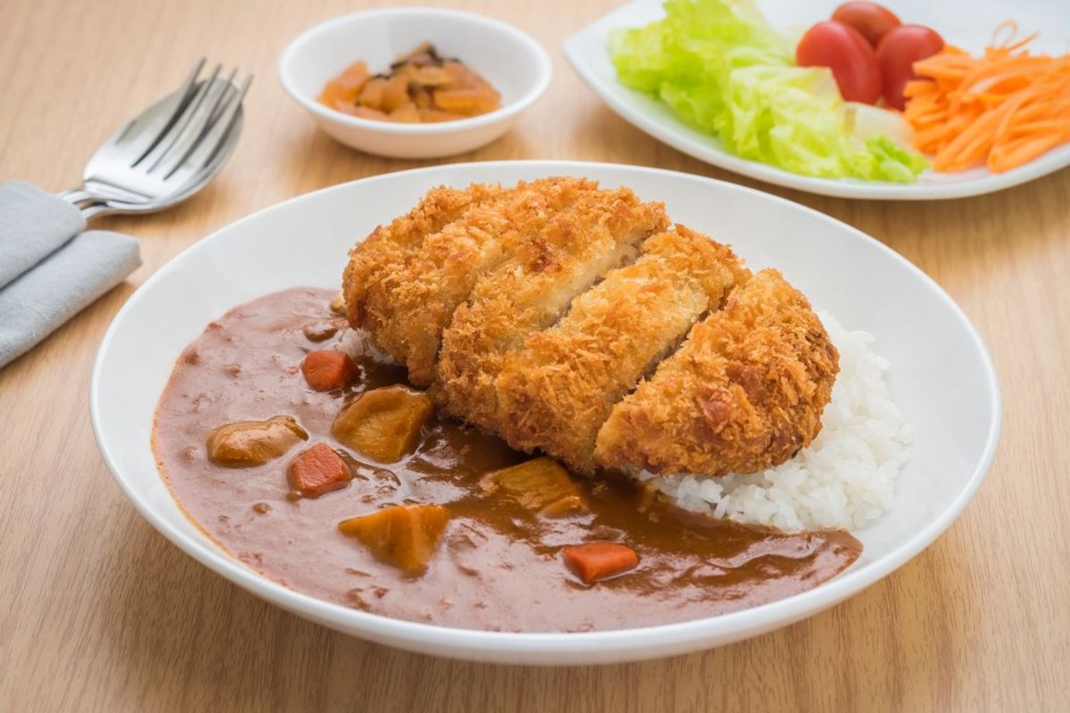 Breaded cutlet with creamy sauce, mashed potatoes, and vegetable side dishes
