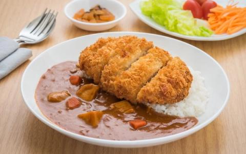 Breaded fried cutlet with creamy sauce, mashed potatoes, and vegetable garnish