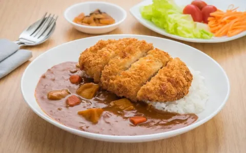Breaded fried cutlet with creamy sauce, mashed potatoes, and vegetable garnish