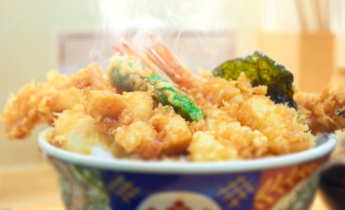 Tempura shrimp and vegetables in decorative bowl with beverage in background